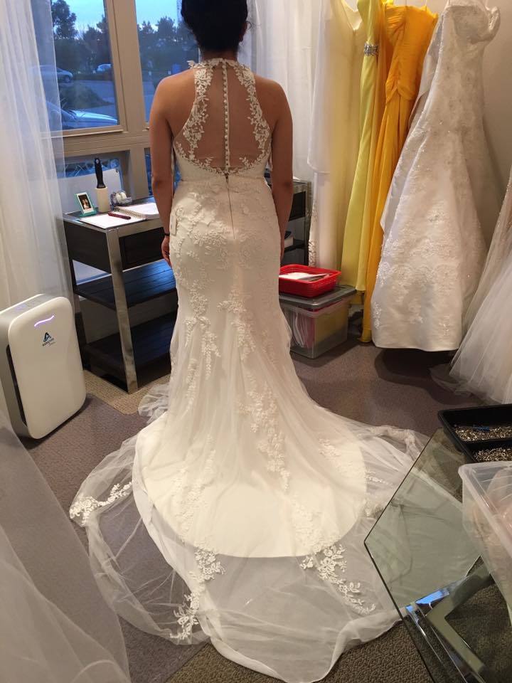 A woman in a wedding dress gazes thoughtfully at her gown, reflecting on her special day ahead.