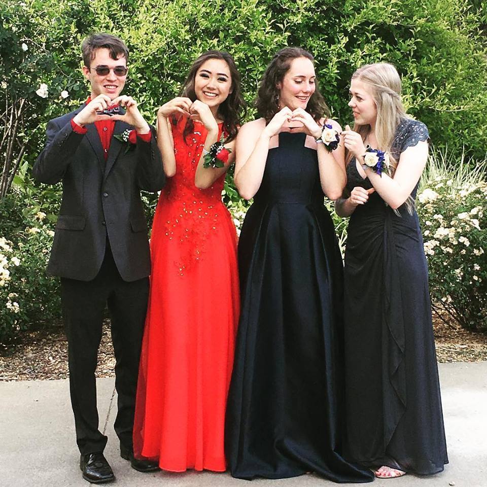 Four young individuals in formal attire smiling and posing together for a group photo.